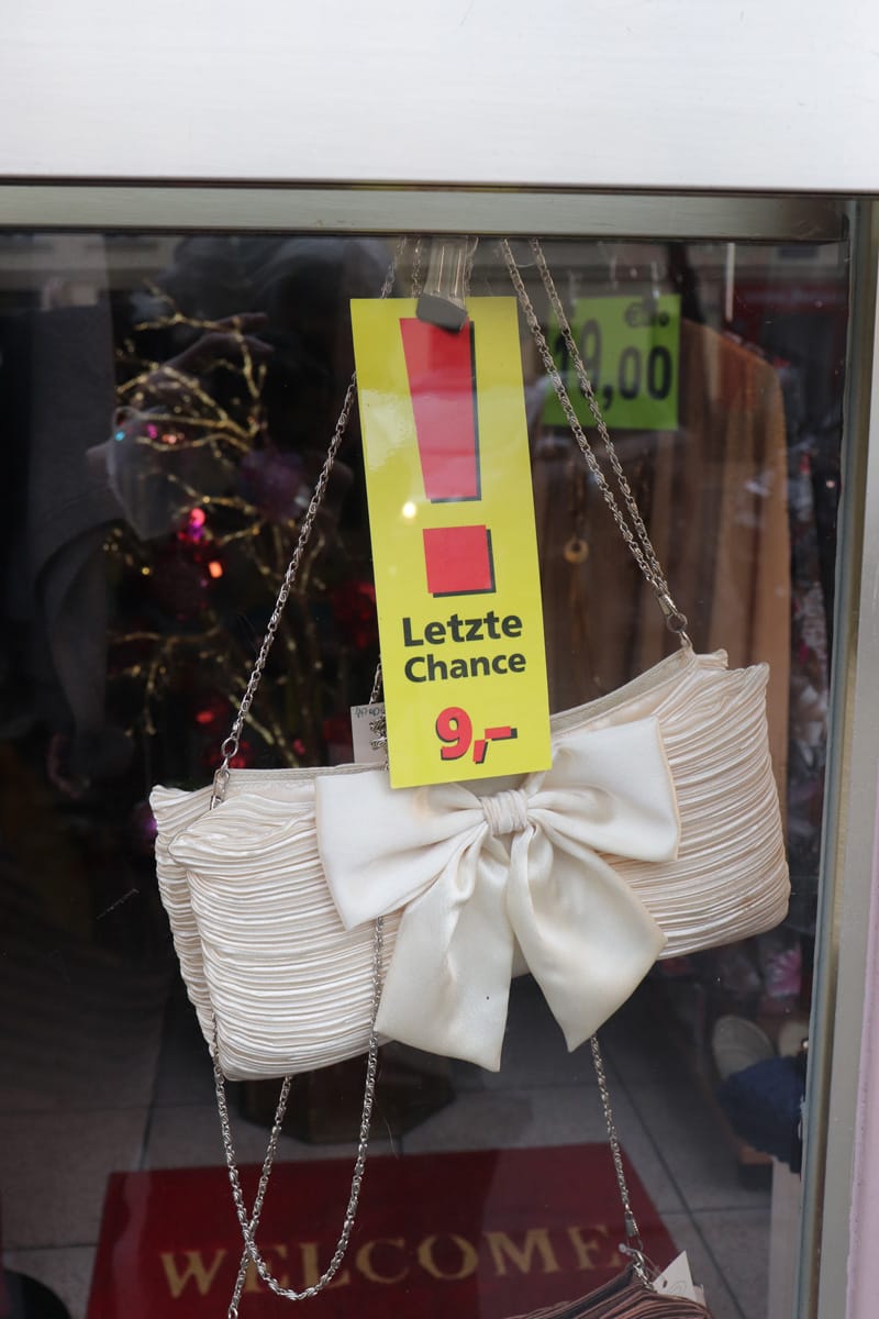 Weisse Handtasche im Ladenfenster, darüber ein Aktionsschild mit der Aufschrift: Letzte Chance 9€