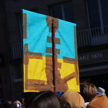Selbstgebautes Demoschild aus Pappe von hinten über den Köpfen von Menschen